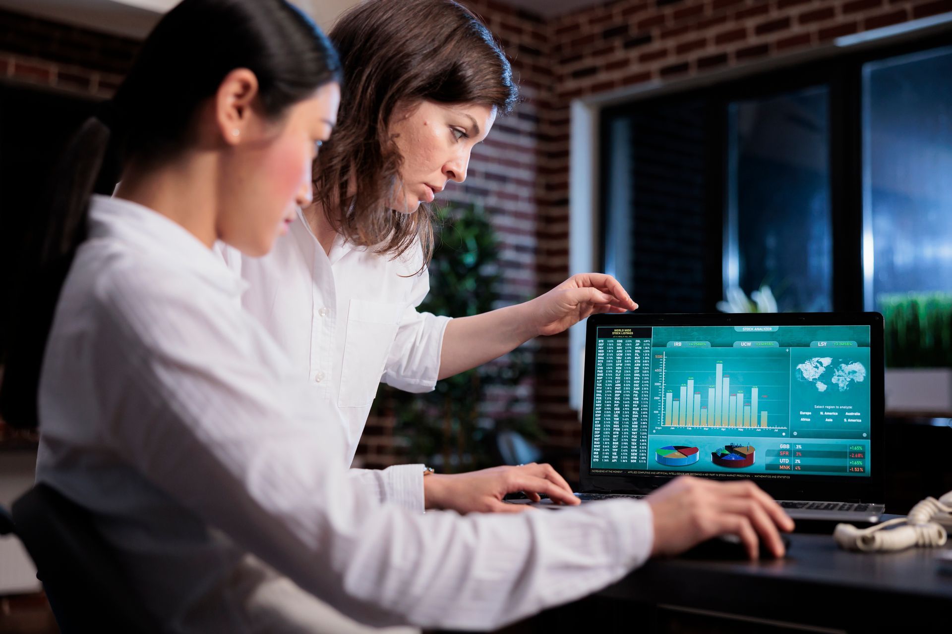 Two women are looking at a laptop computer.