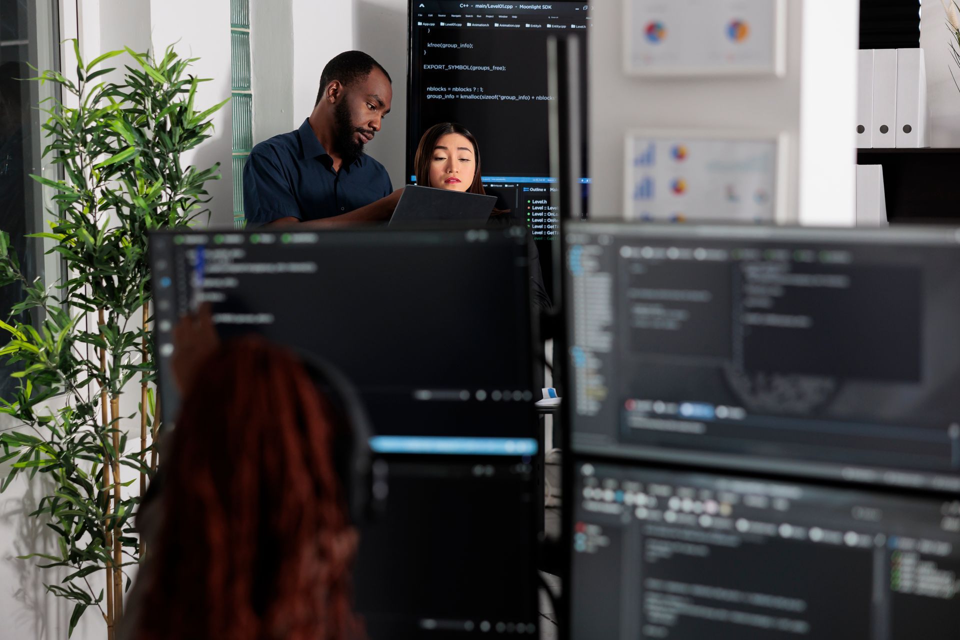 A man and a woman are sitting in front of computer monitors.