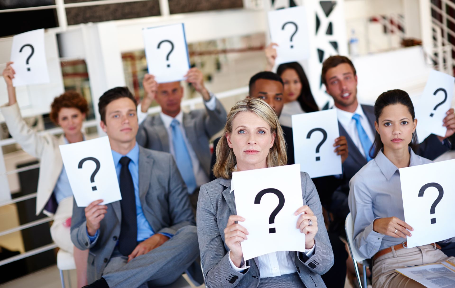 A group of people are holding up signs with question marks on them.