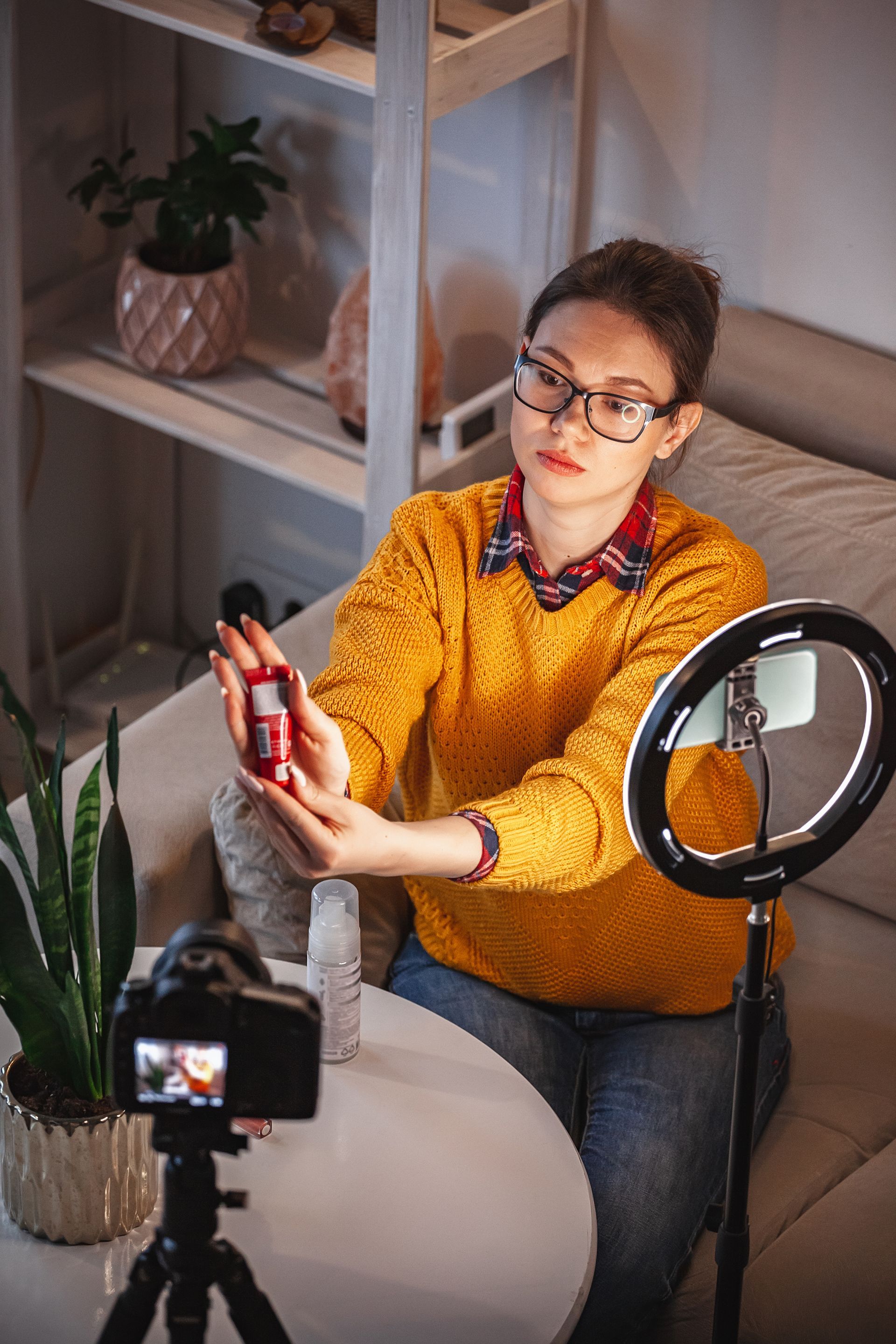 A woman is sitting at a table with a camera and a ring light.