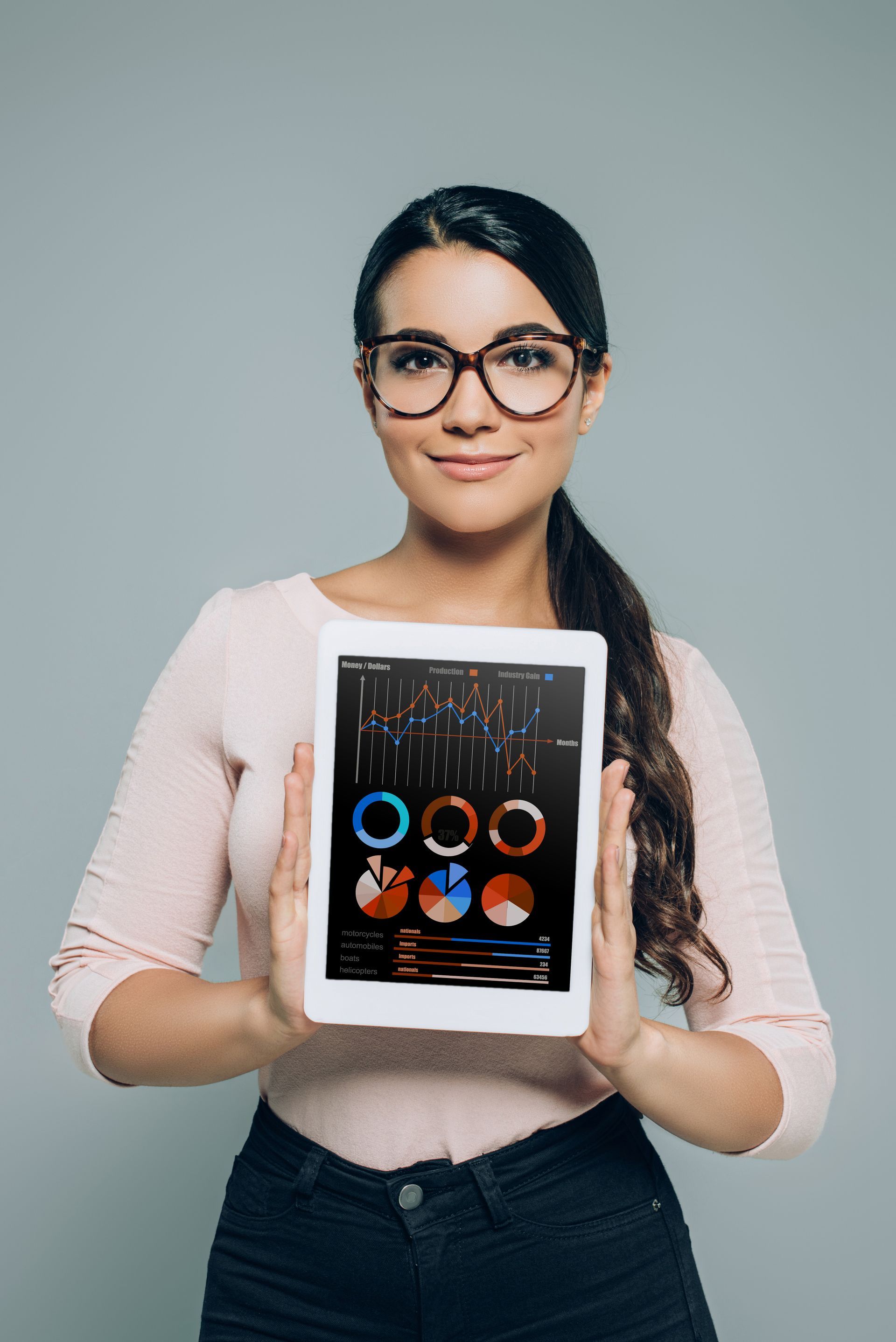 A woman is holding a tablet with graphs on it.
