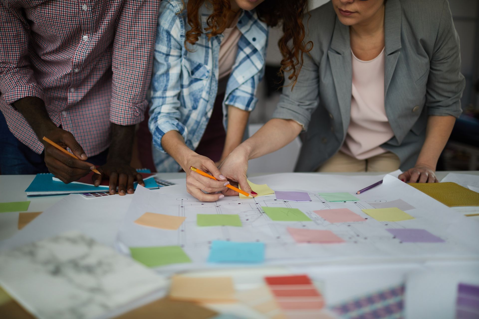 A group of people are sitting at a table looking at sticky notes.