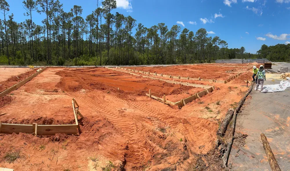 A construction site with a lot of dirt and trees in the background.