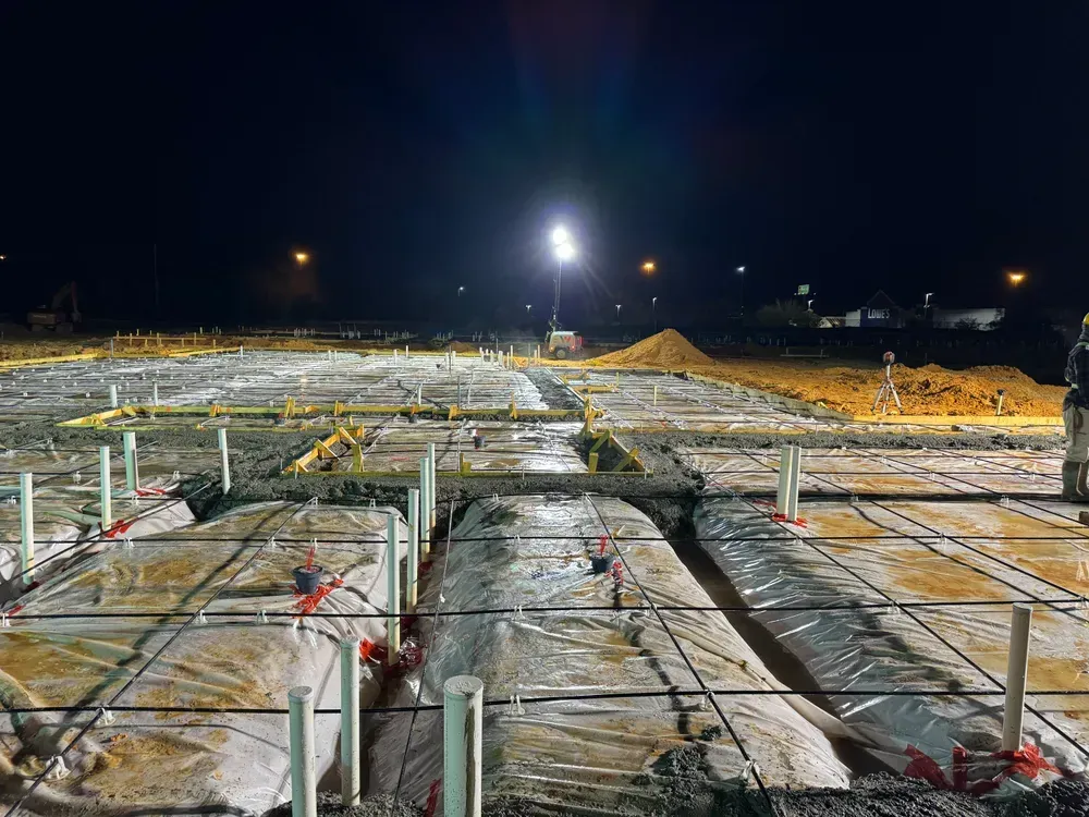 A construction site is being built at night with a lot of pipes.