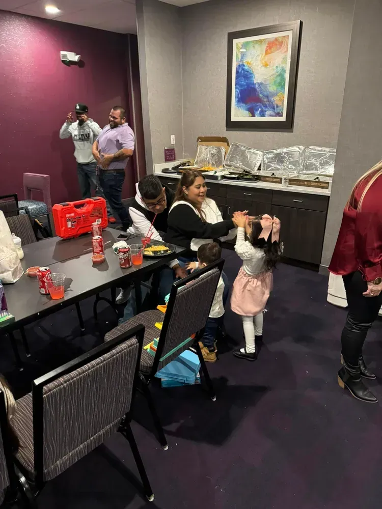 A group of people are sitting at tables and chairs in a room.