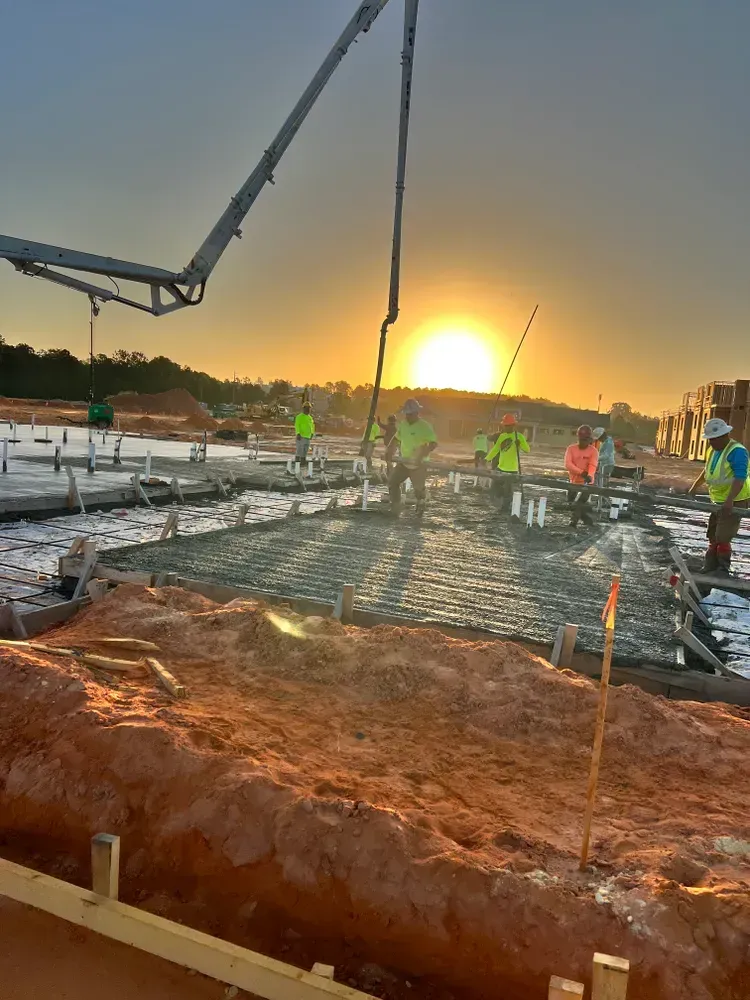 A group of construction workers are working on a construction site at sunset.