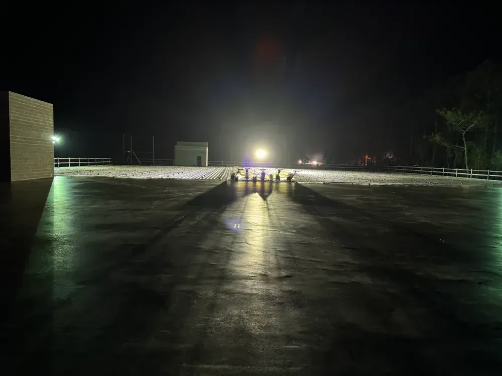 A helicopter is flying over a snowy field at night.