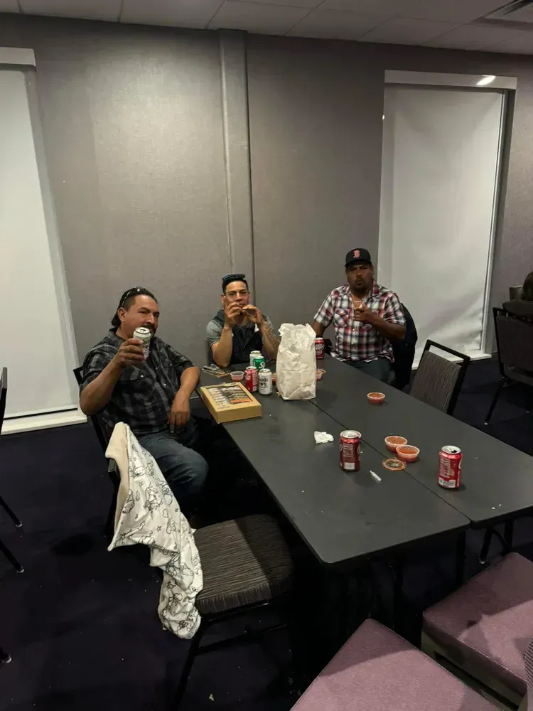 A group of men are sitting around a table drinking beer and eating food.