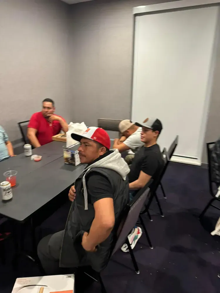 A group of men are sitting around a table in a room.