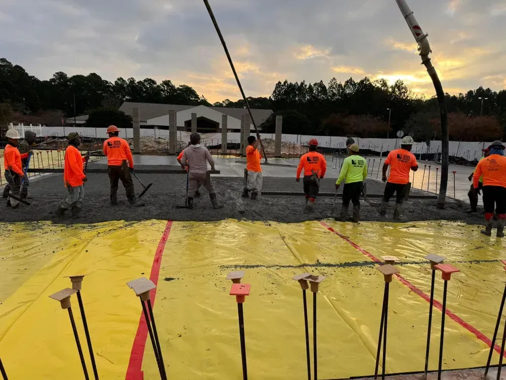 A group of construction workers are standing on top of a yellow tarp.