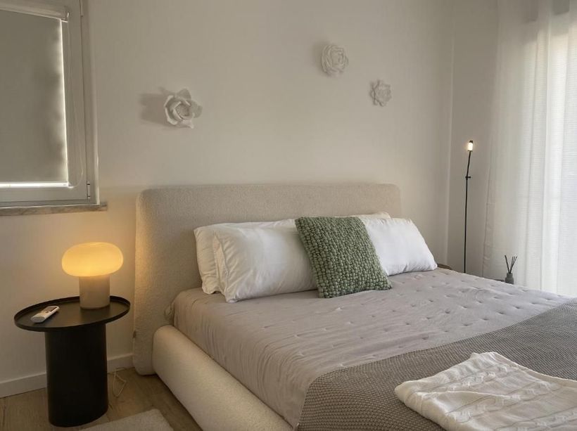 A bedroom with bed, bedside table, lamp and mirror.