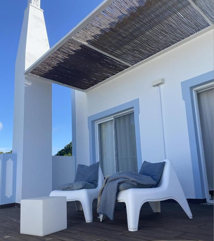 A patio with two chairs and a stool under a canopy