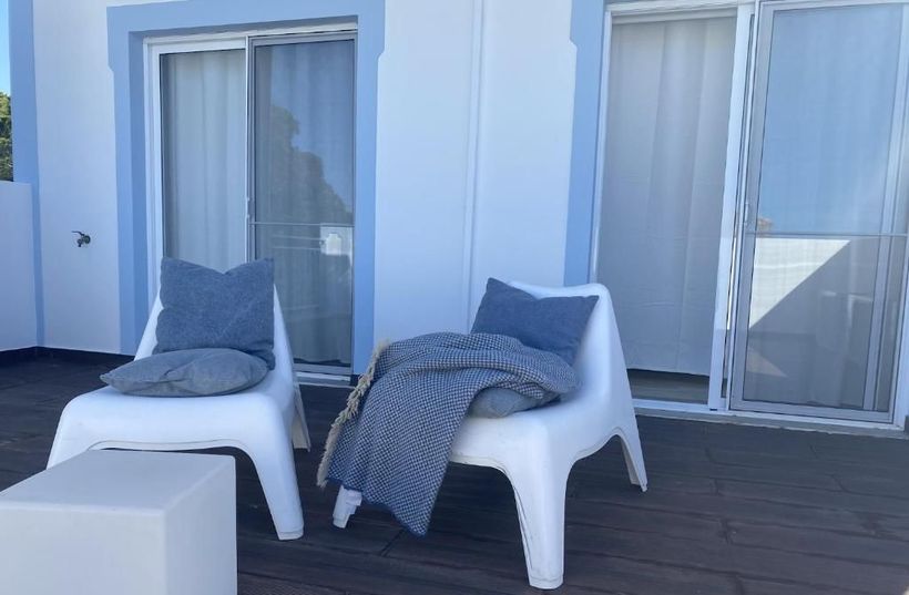Two white chairs are sitting on a wooden deck in front of a building.