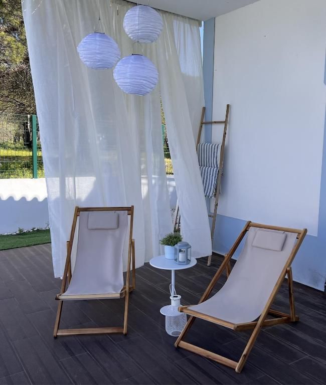 Two garden chairs and a table under a white curtain