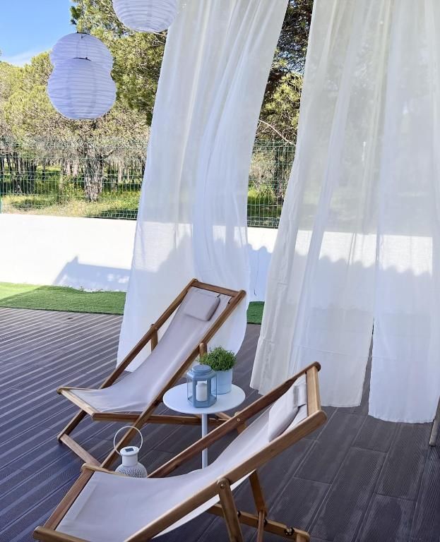 Two garden chairs under a canopy with white curtains