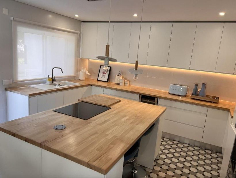 A kitchen with white cabinets and wooden countertops.