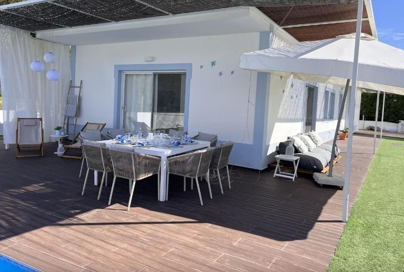 There is a table and chairs on the deck of a house.