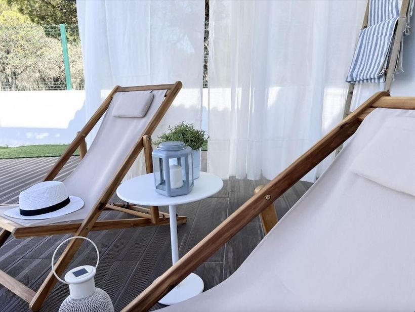 Two lawn chairs are next to a table with a lantern.