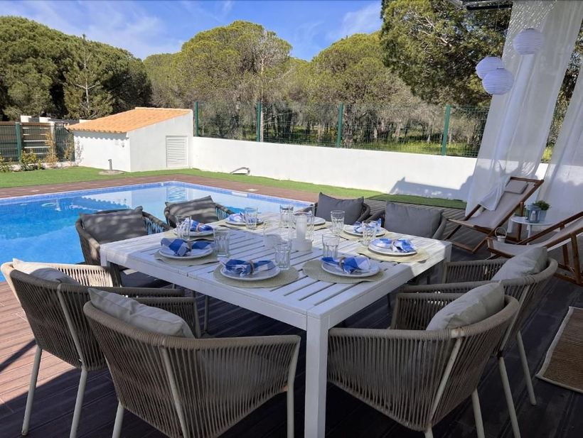 There is a table and chairs in front of a pool.