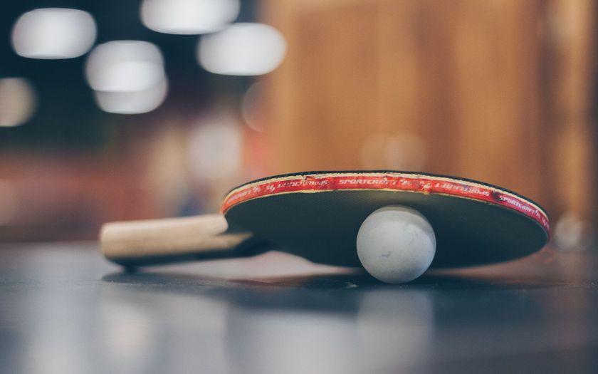 A ping pong paddle and ball are on a table.