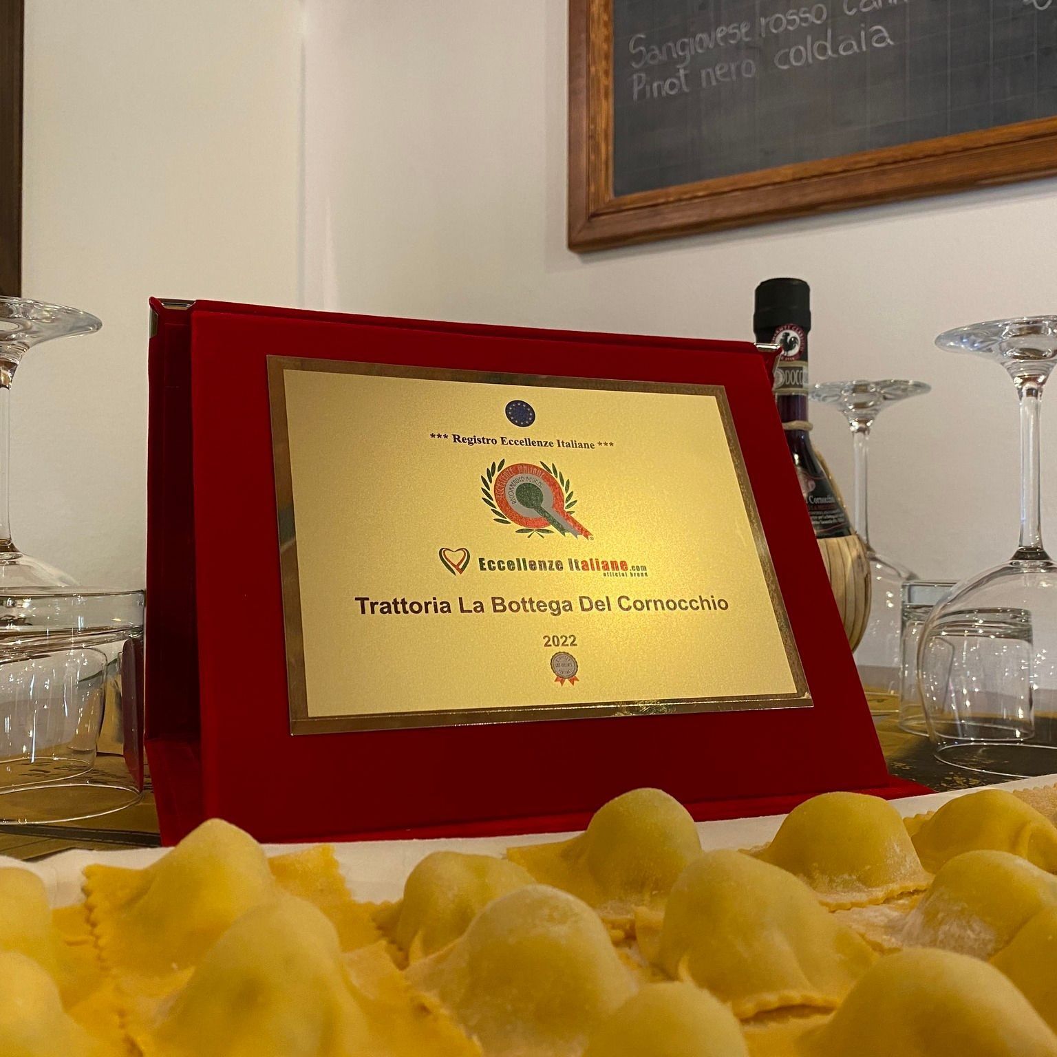 Award plaque for Trattoria La Montagna Dei Cornacchie restaurant with pasta.