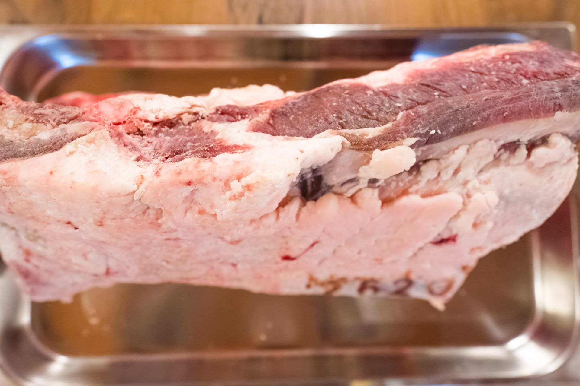 Petto di manzo crudo in un vassoio di acciaio inossidabile, con spessi strati di grasso.
