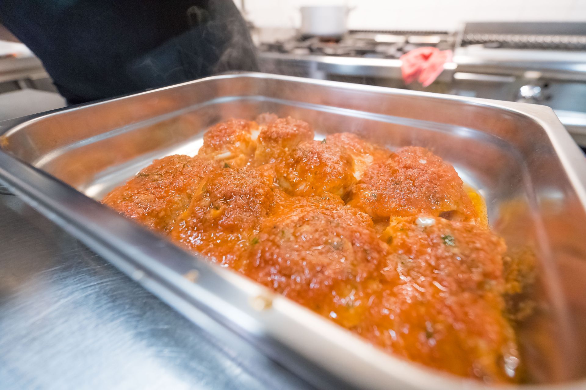 Polpette in salsa di pomodoro in una teglia di metallo, cotte a vapore in cucina.