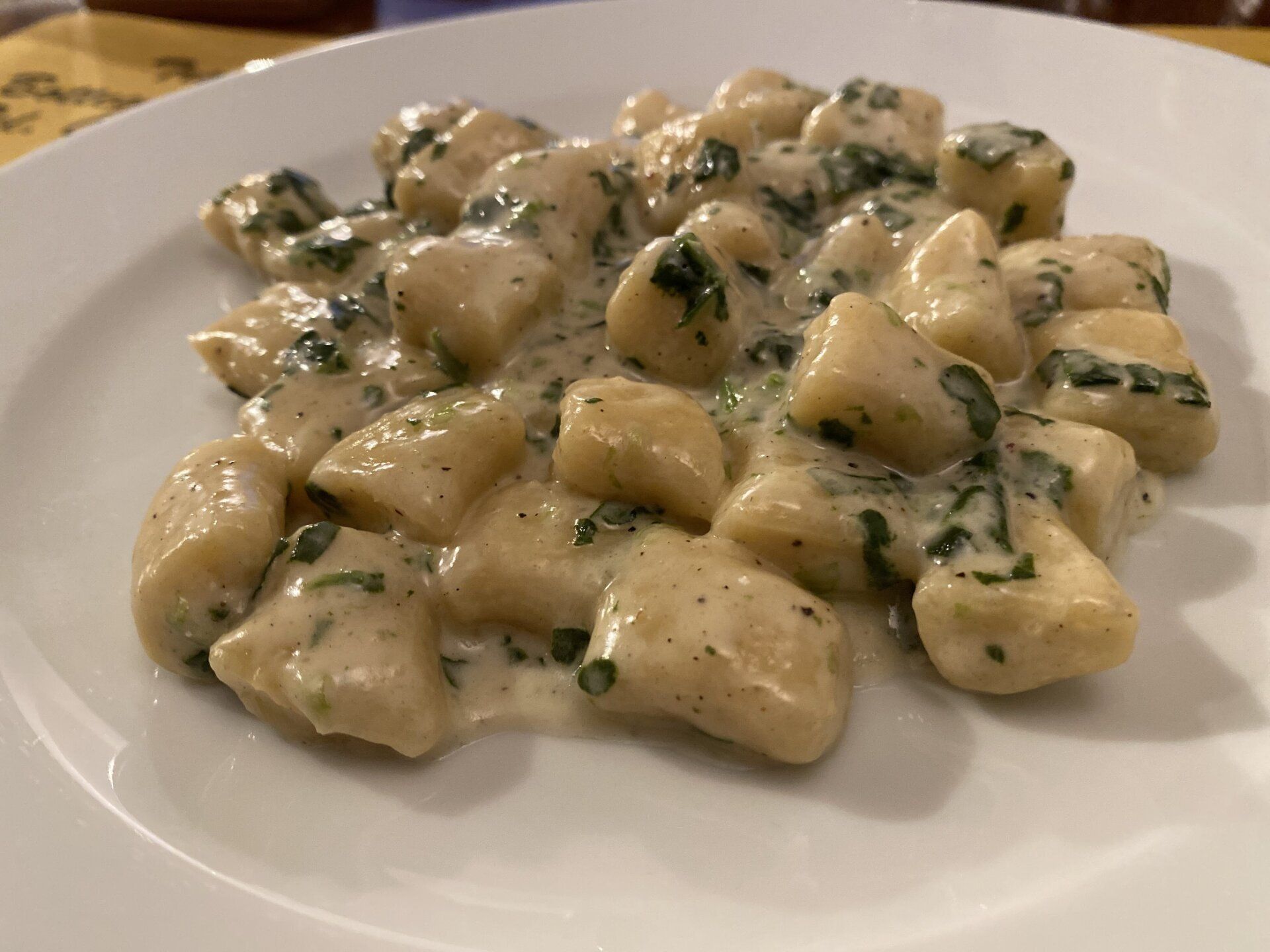 Gnocchi con salsa cremosa e spinaci su un piatto bianco.