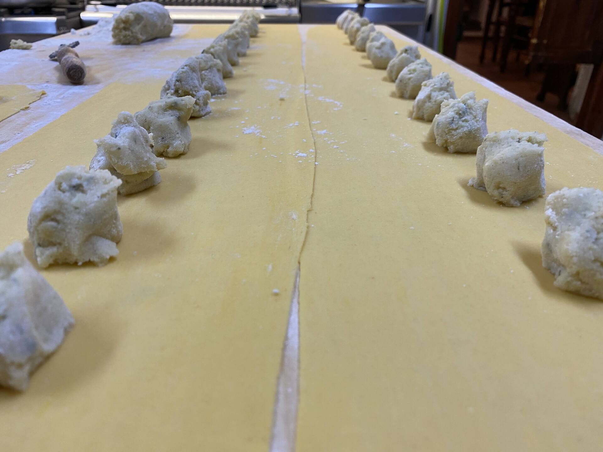 Pasta con file di pezzi di pasta, pronti per essere farciti, su un tavolo.