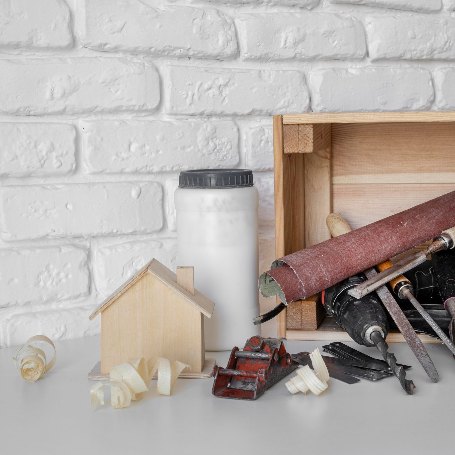 A wooden box filled with woodworking tools and a small wooden house.