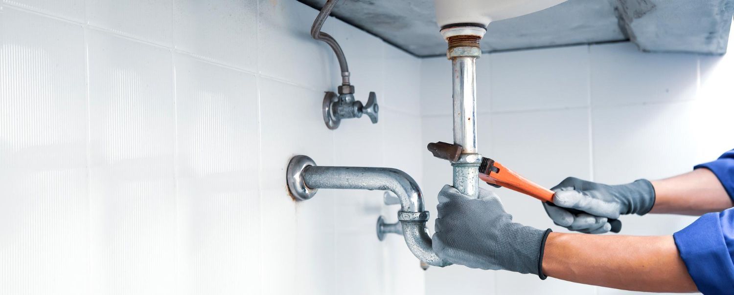 A plumber is fixing a sink with a wrench.