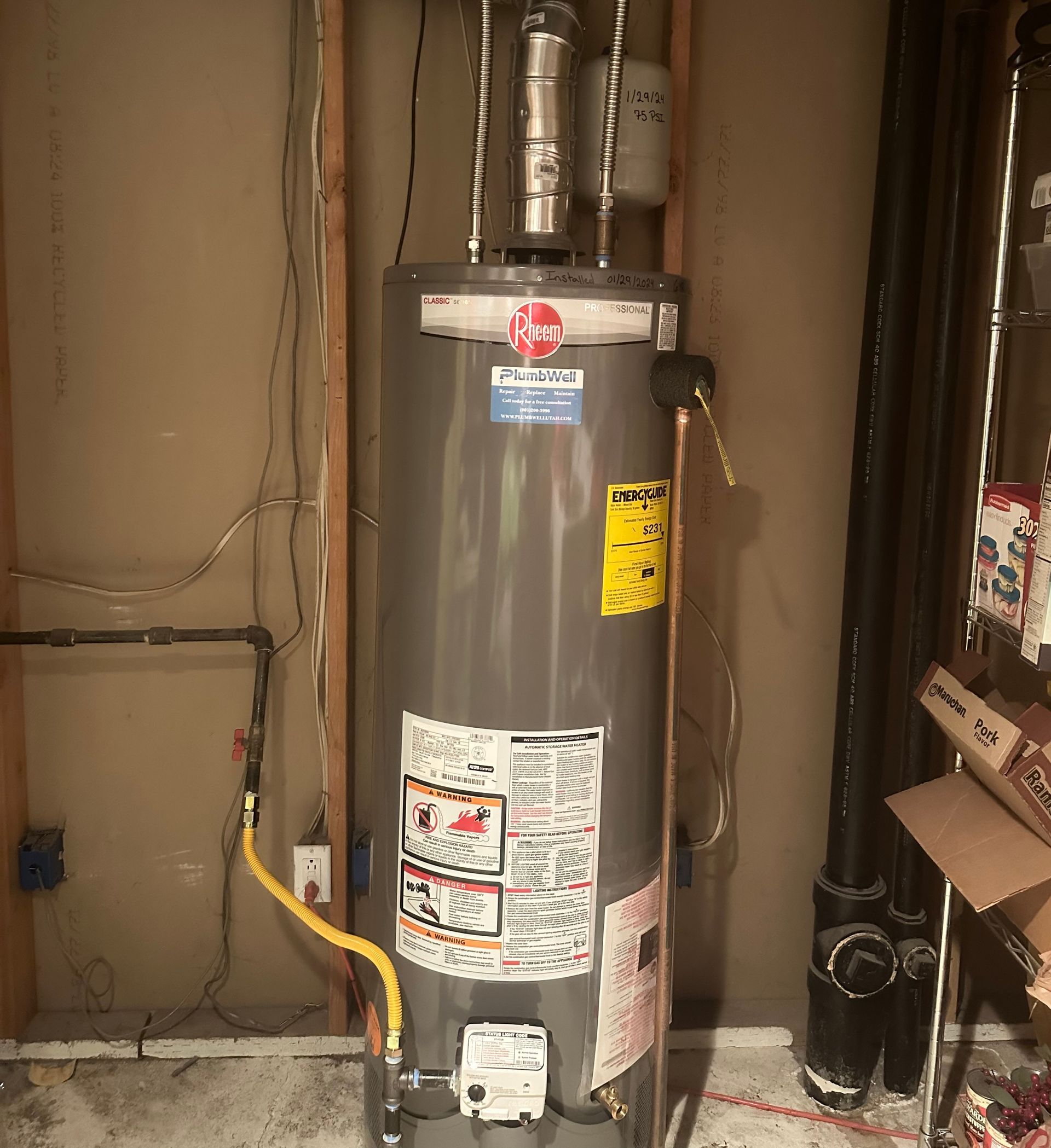 A gray water heater is sitting in a room next to a wall.