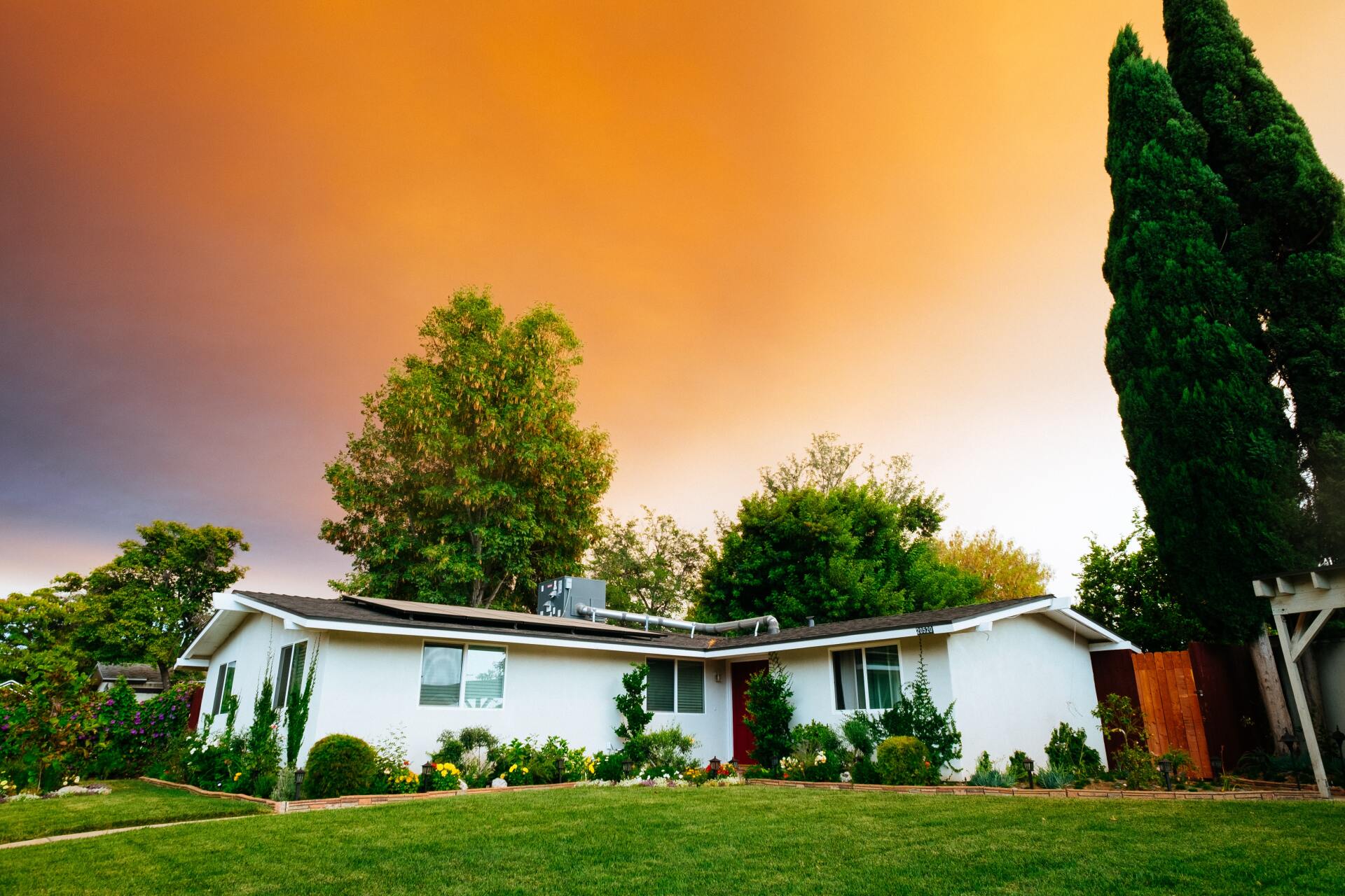 A white house with a lush green lawn in front of a cloudy sky.