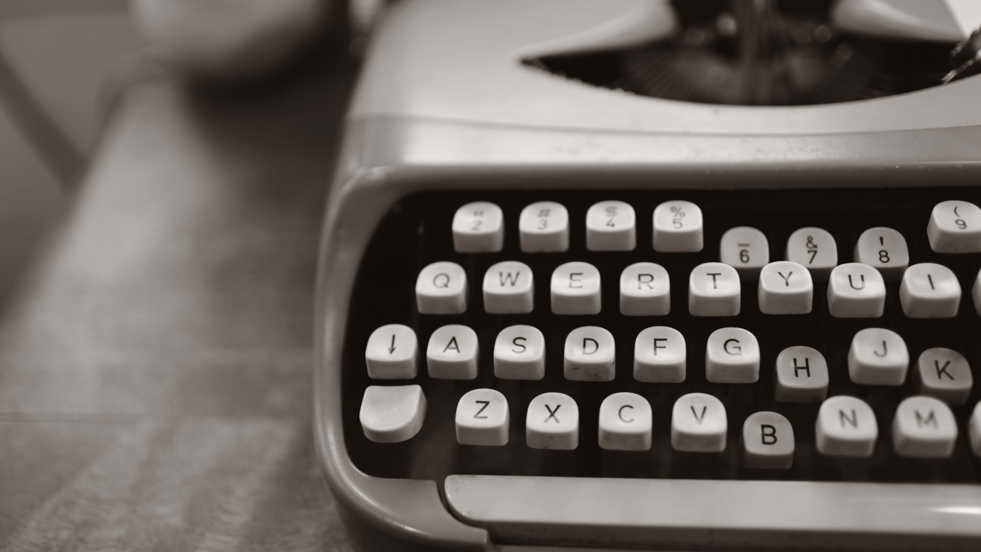 An old typewriter is sitting on a wooden table.