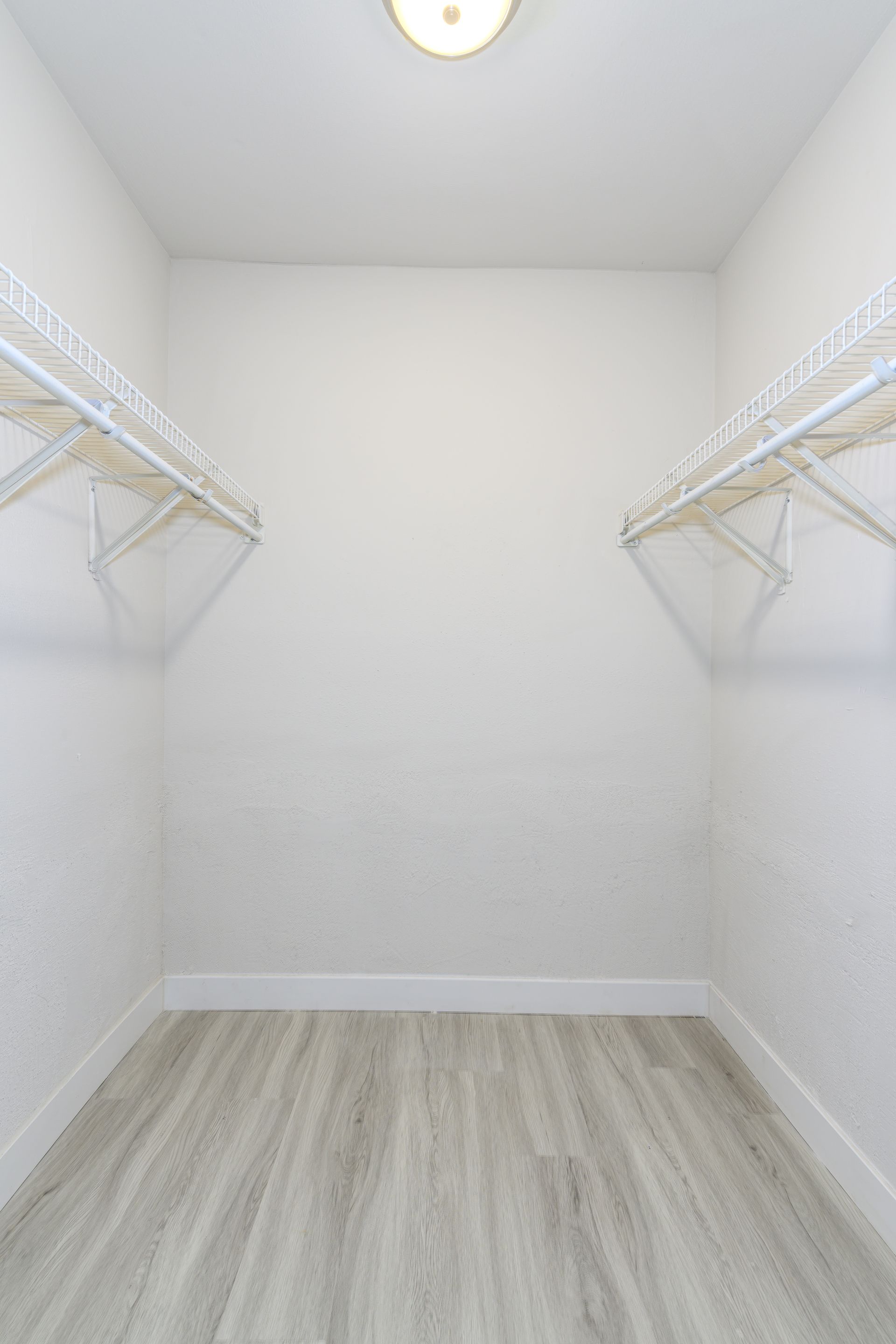 An empty walk in closet with wooden floors and shelves.