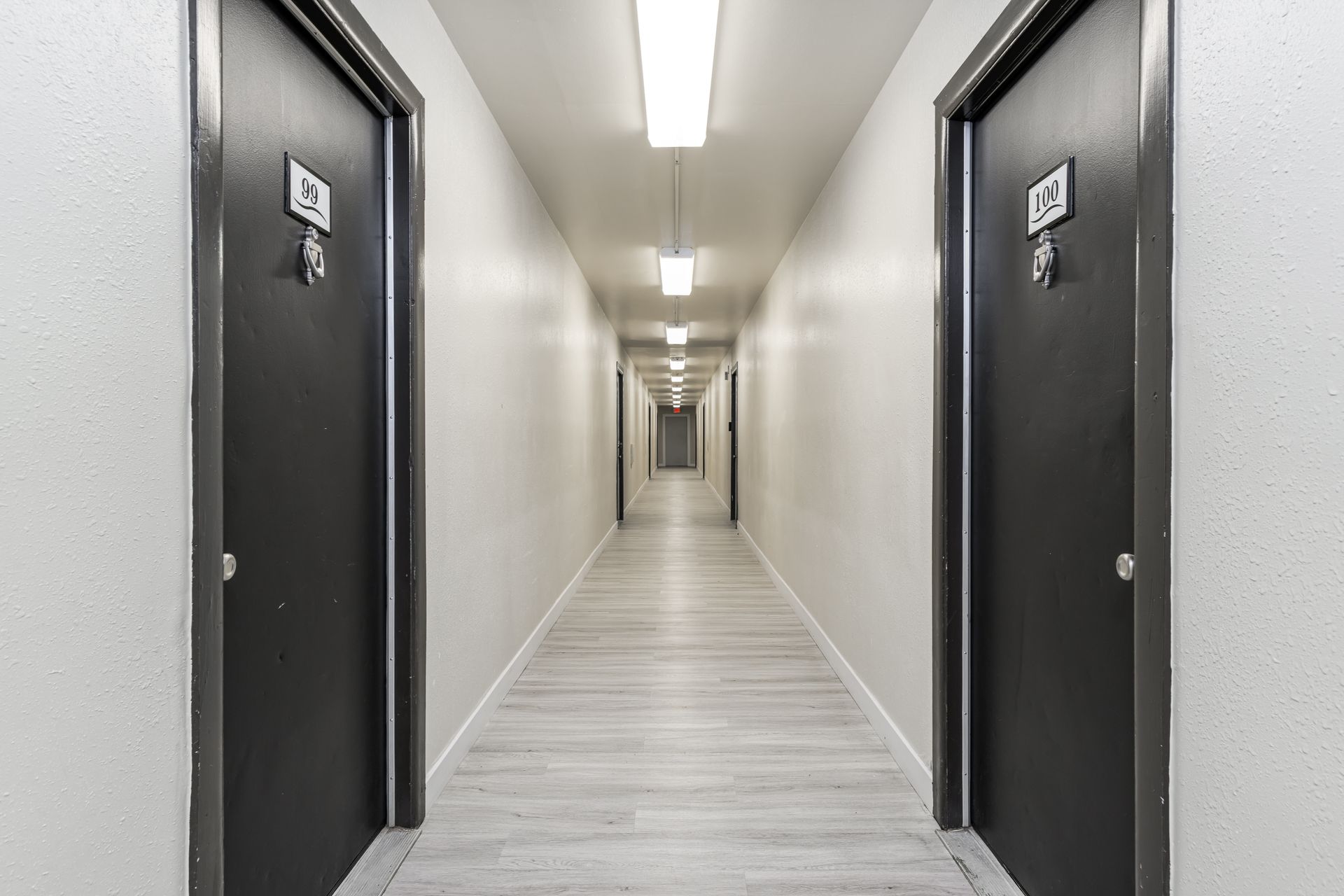 A long hallway with two black doors in a building.