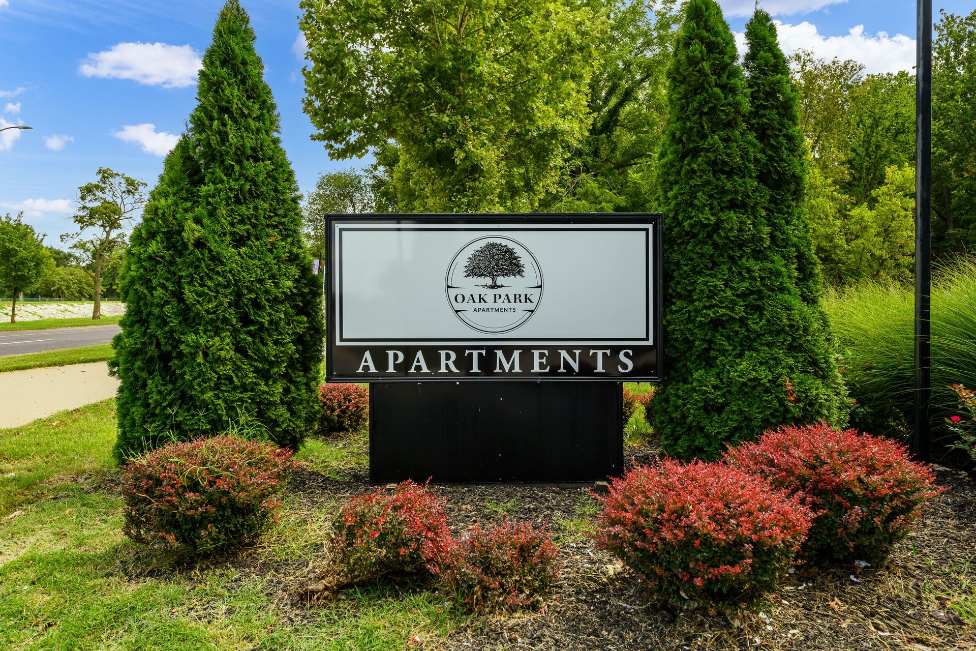 A sign for apartments is surrounded by trees and bushes