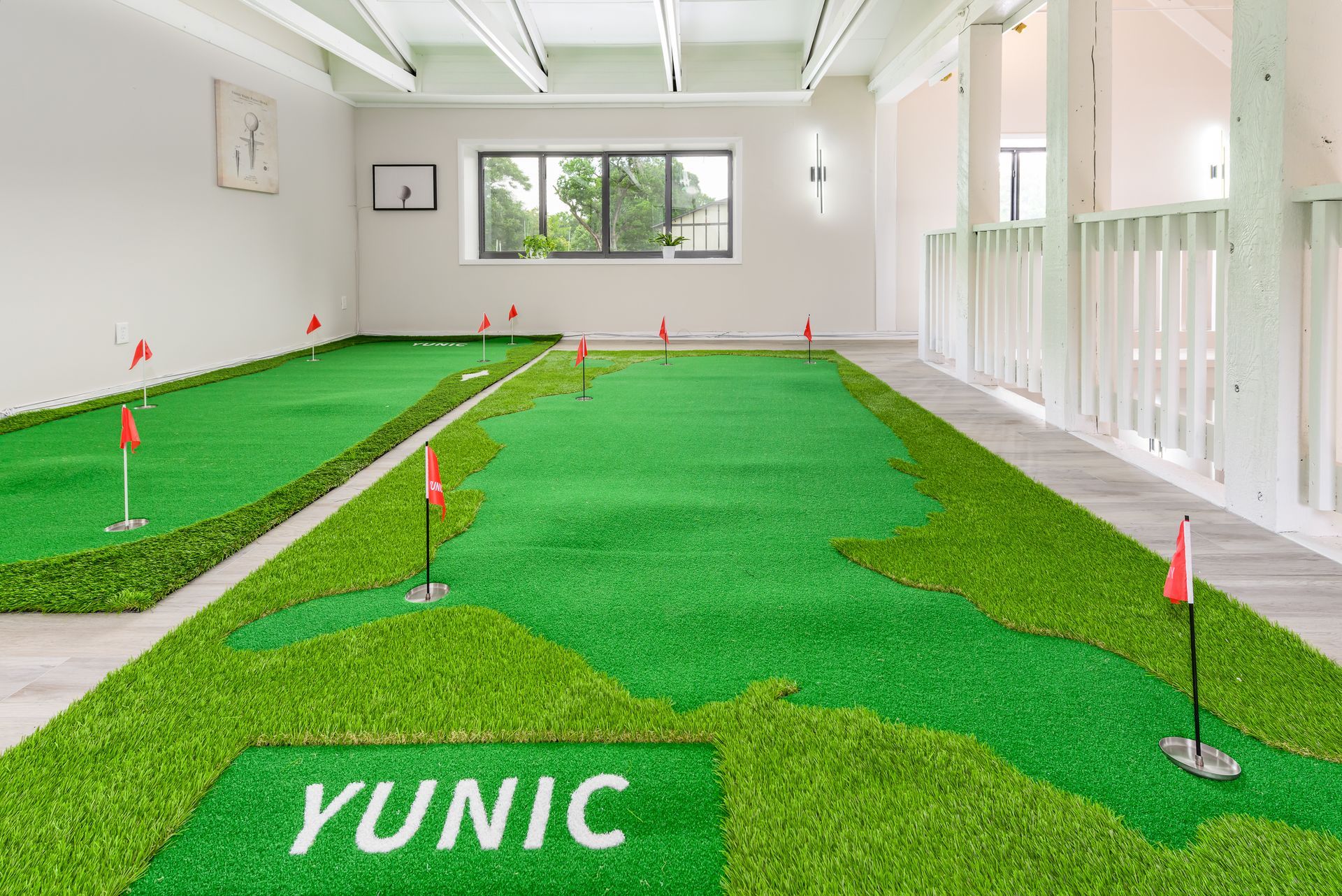 A large room filled with green grass and a putting green.