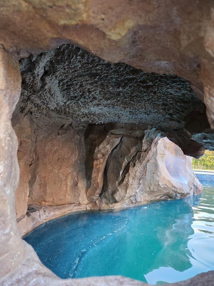 Cave-like structure with blue water; rock formation with overhang.