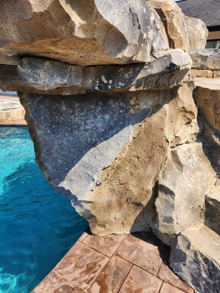 Stone structure over a pool with turquoise water. Structure has tan and gray tones.