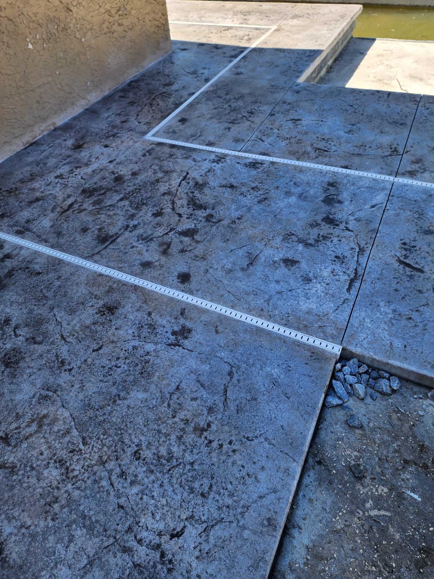 Grey, textured concrete patio with straight lines, possibly a construction project.