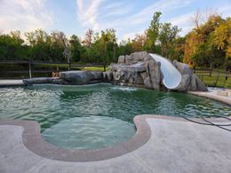 Swimming pool with rock waterfall feature and waterslide.