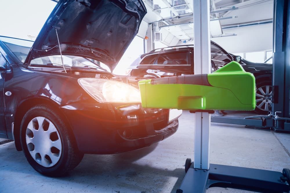 A Car With Its Hood Up Is Sitting On A Lift In A Garage — Vehicle Inspections & Mechanical Services in Albury, NSW