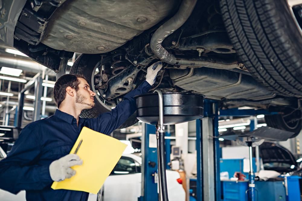 A Mechanic Is Examining The Underside Of A Car In A Garage — Affordable Mechanic in Albury, NSW