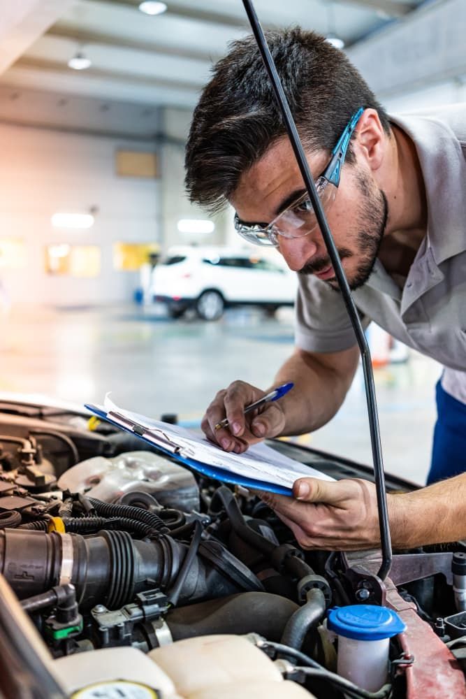 A Man Is Looking Under The Hood Of A Car And Writing On A Clipboard — Providing Mechanical Repairs in Albury, NSW
