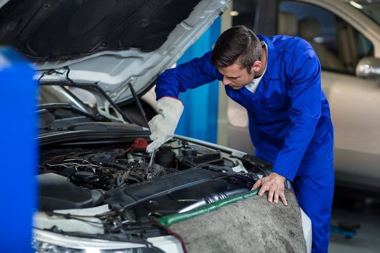 A Mechanic Is Working Under The Hood Of A Car In A Garage — Your Experienced Mechanic in Wodonga, VIC