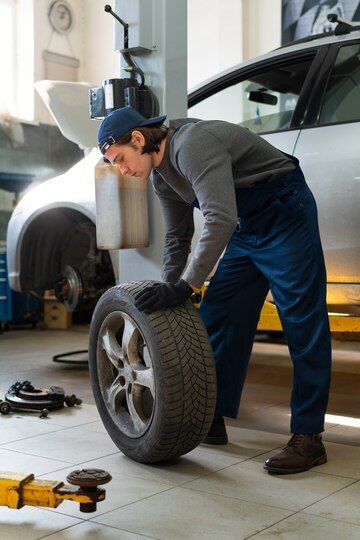 A Man Is Changing A Tire In A Garage — Your Experienced Mechanic in Wodonga, VIC