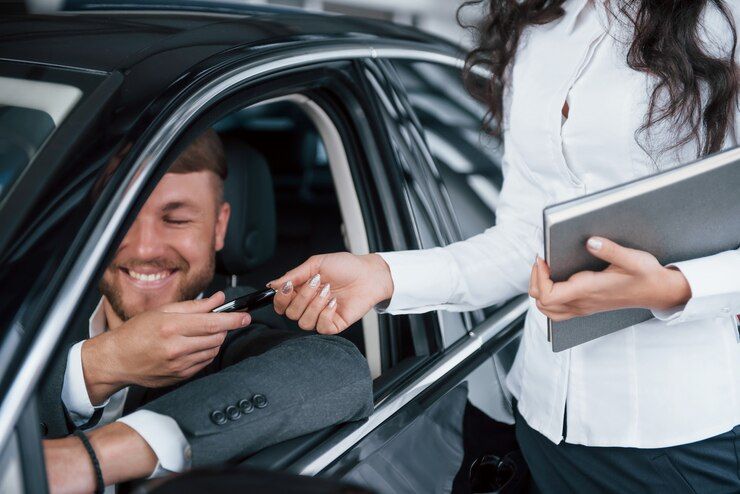 A Woman Is Handing A Car Key To A Man In A Car — Experienced Car Mechanic in Albury, NSW
