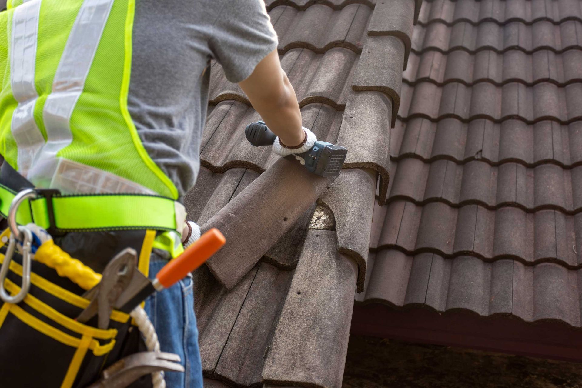 A roofer replacing damaged roof tiles during a residential roof repair. A roofer replacing damaged roof tiles during a residential roof repair.