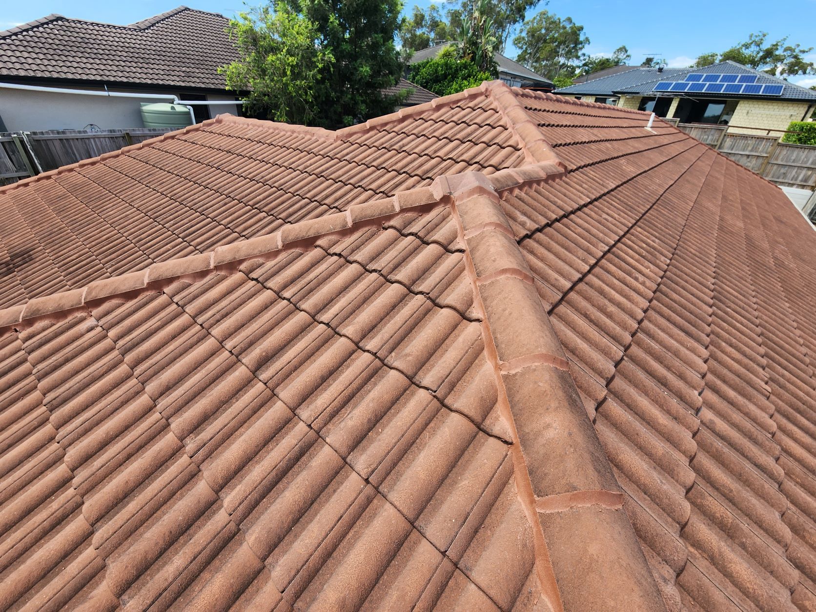 A view looking down over a terracotta-tiled roof with a central ridge line and adjoining pitched sections.